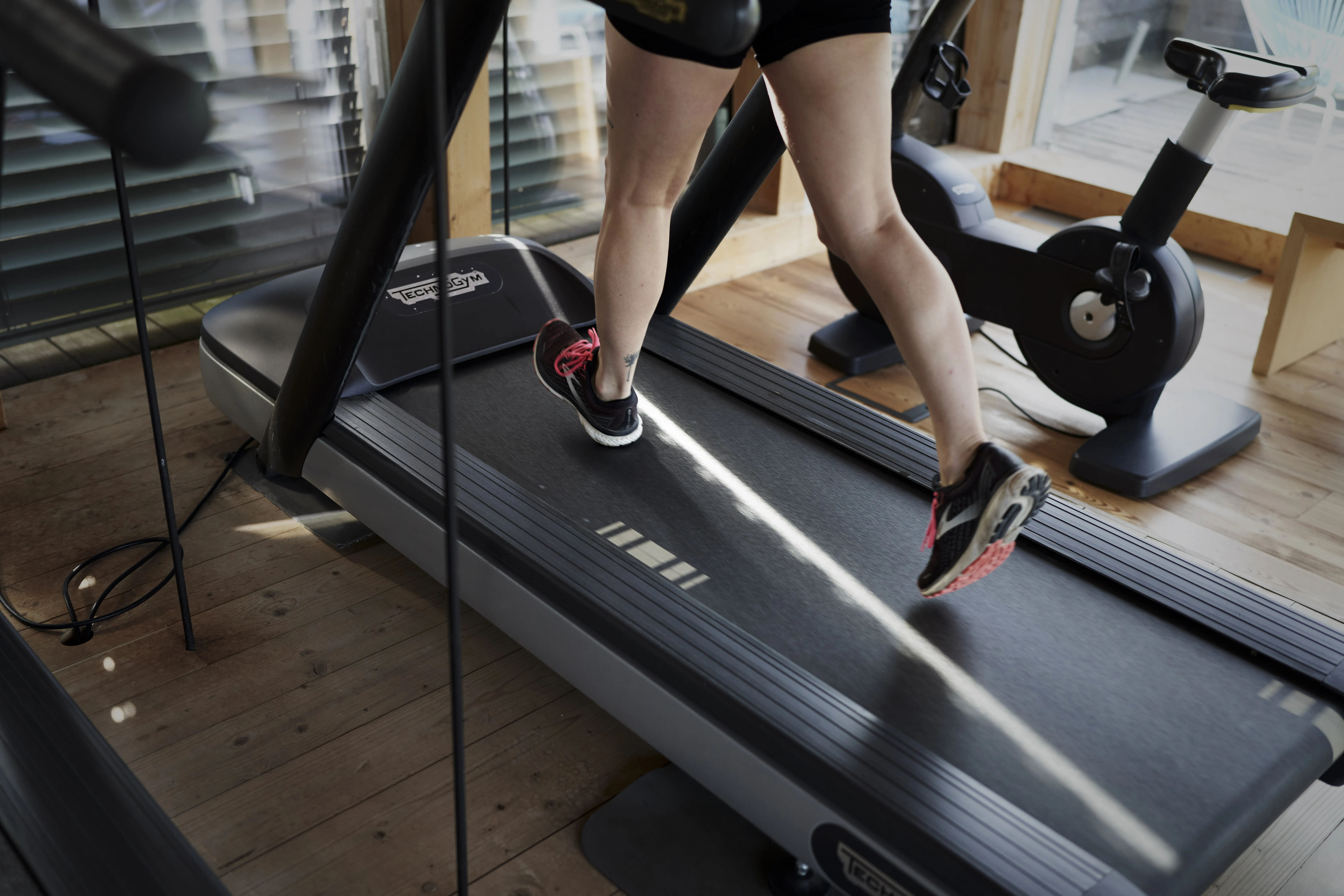 Nahaufnahme von Füßen auf einem Laufband in einem Fitnessbereich.