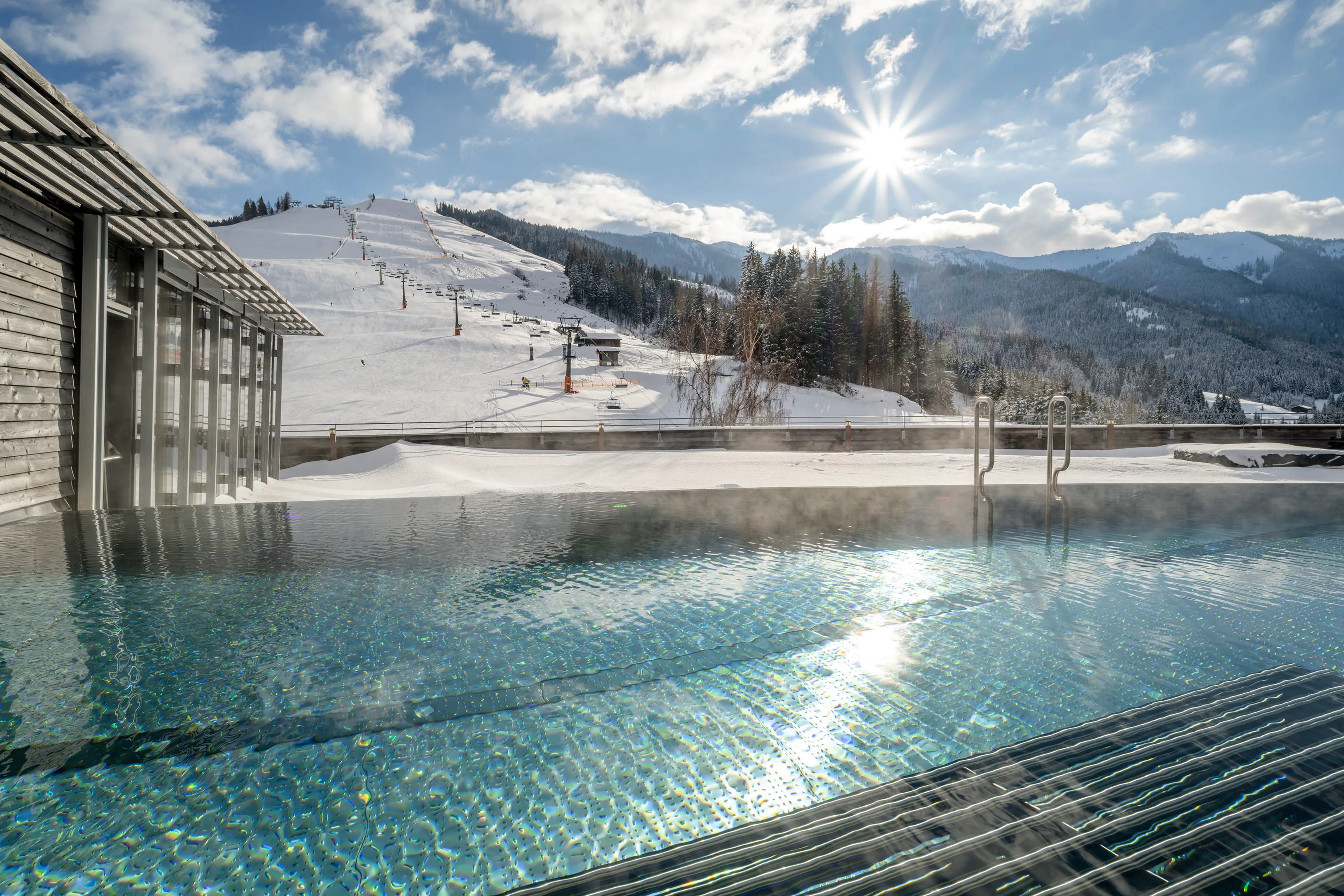 Pool des Holzhotels Forsthofalm mit schneebedeckten Bergen im Hintergrund