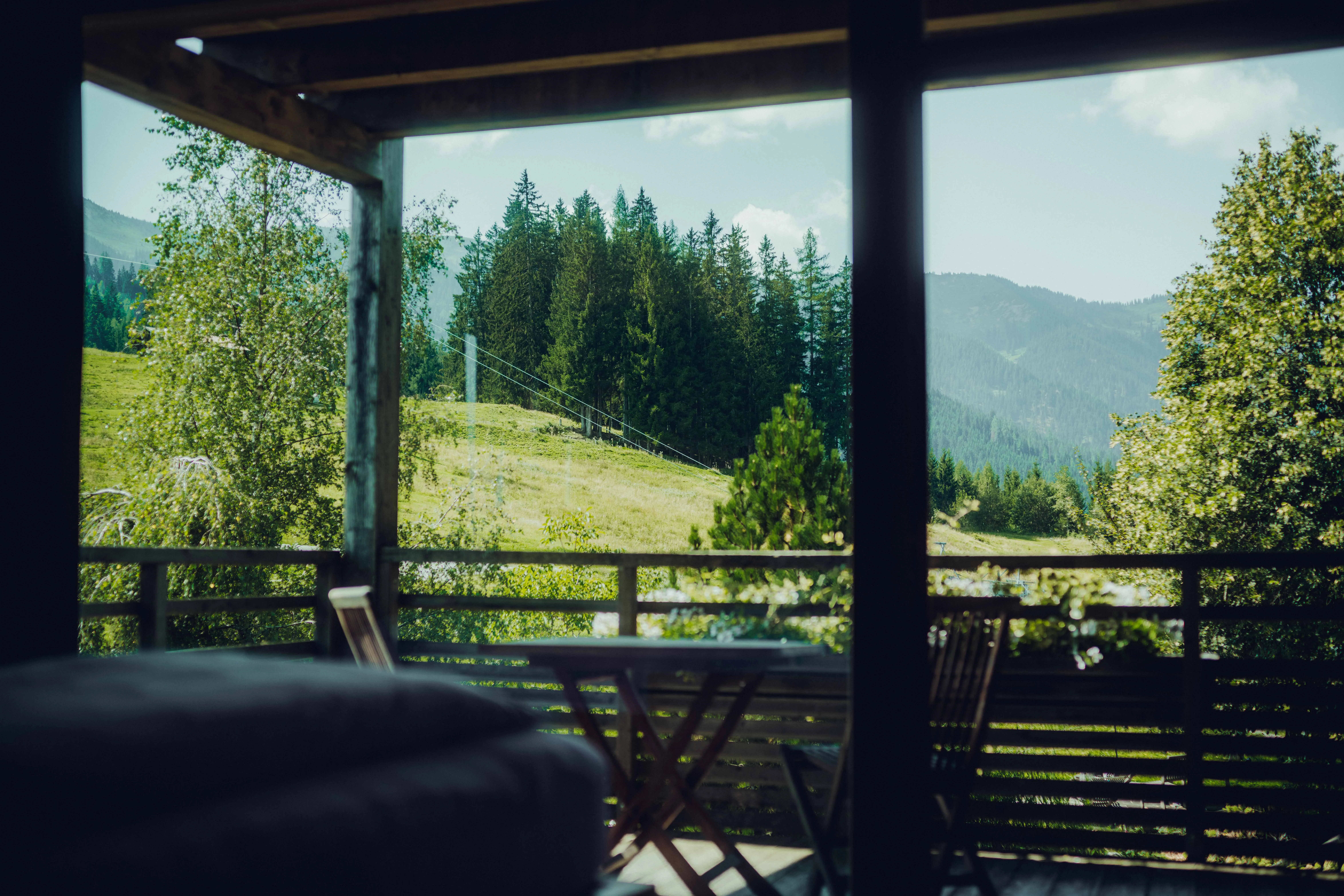 Blick von einem Balkon auf eine grüne Landschaft mit Bäumen und Bergen.