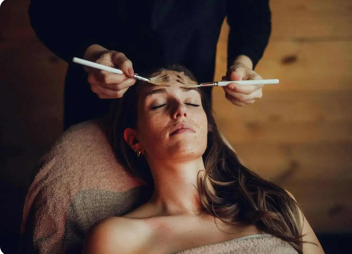Frau erhält Wellness-Behandlung mit einer Hand auf ihrem Gesicht.