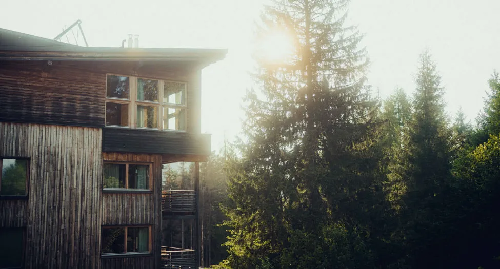 Holzhotel Forsthofalm in Leogang, umgeben von Bäumen und Sonnenlicht
