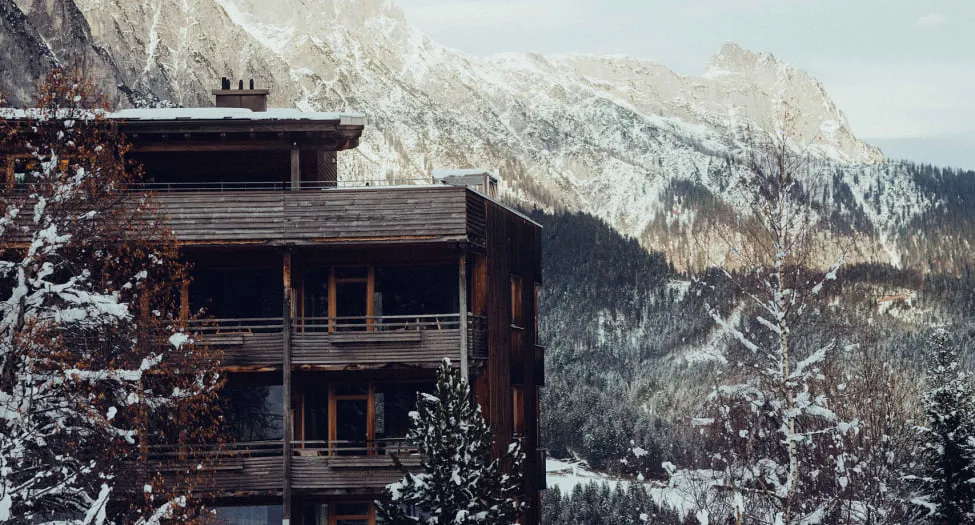 Holzhotel Forsthofalm in Leogang mit schneebedeckten Bergen im Hintergrund