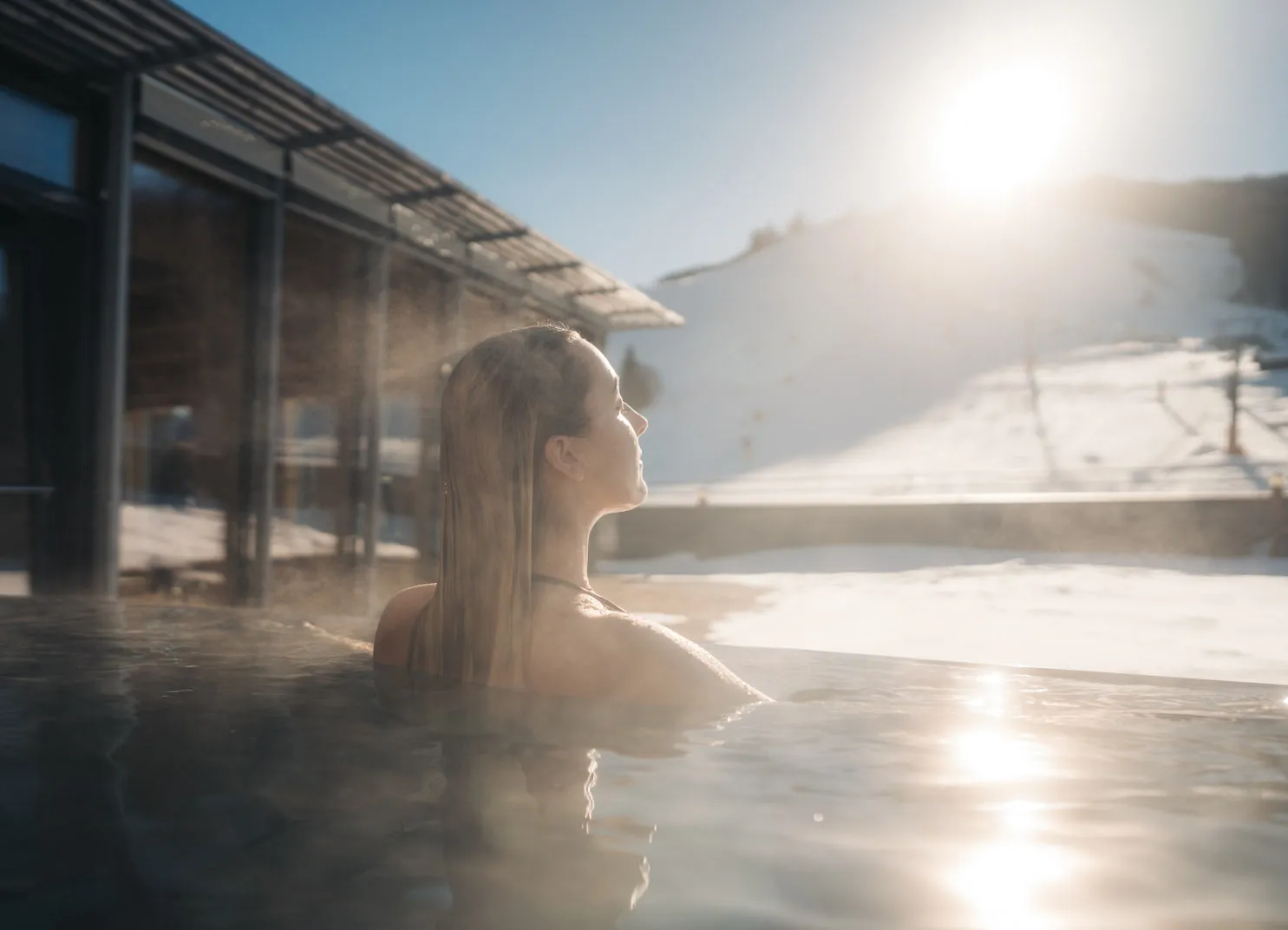 Frau im Wasser eines Außenpools mit Schnee im Hintergrund