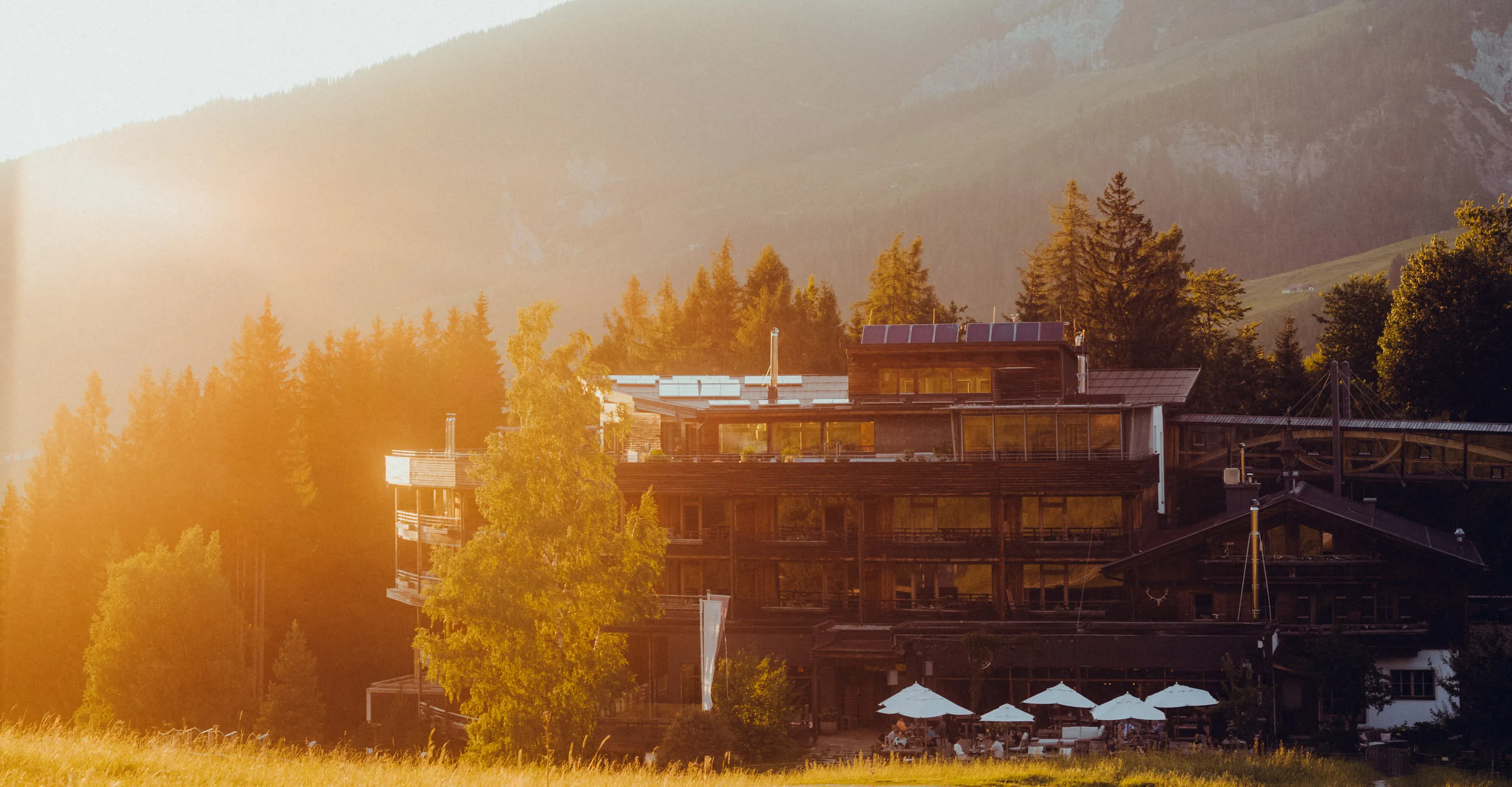 Berglandschaft mit Hotel und Sonnenschirmen im Vordergrund