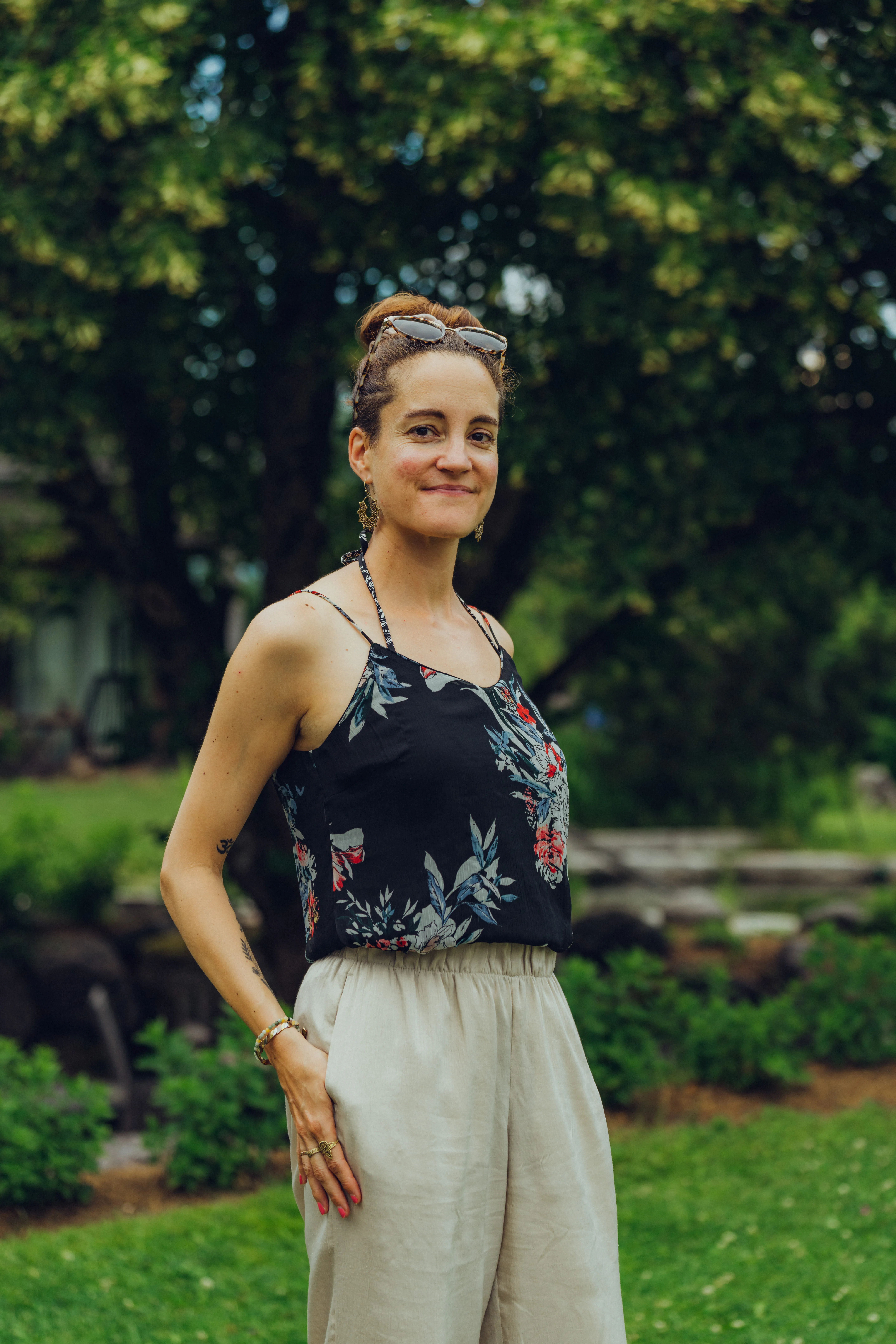 Frau in floralem Top und weißen Hosen im Garten